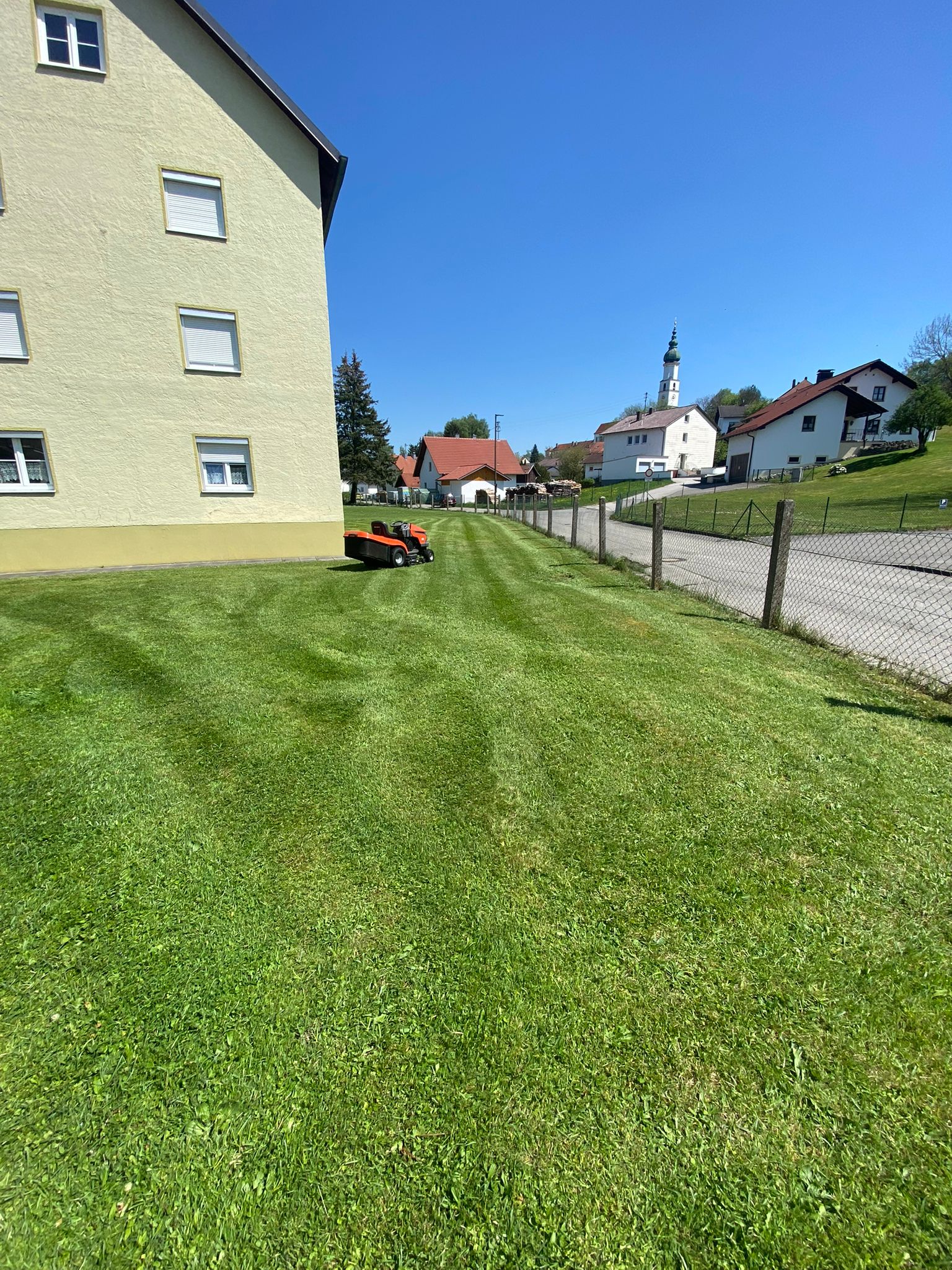 Frisch gemähter Rasen neben einem Wohnhaus